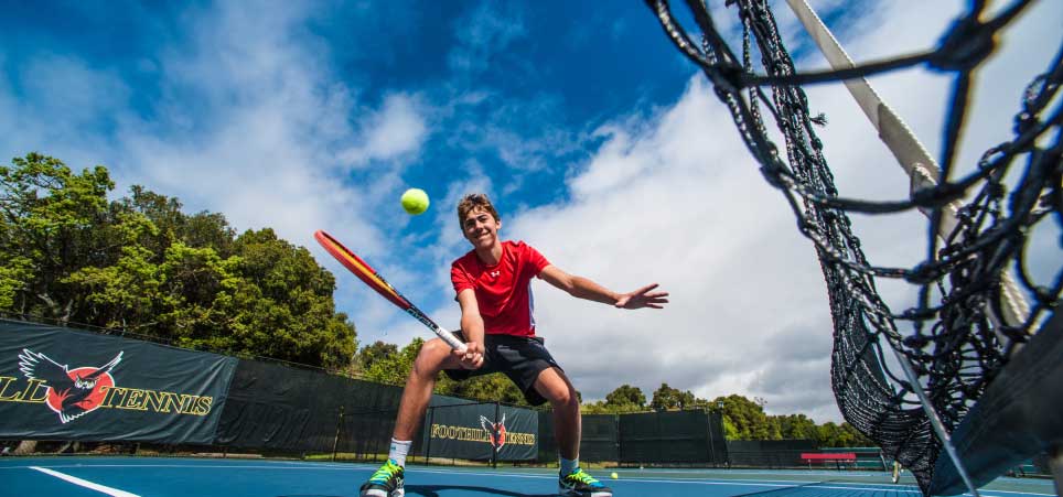 male student playing tennis